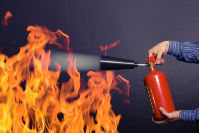 Man using a fire extinguisher on flames
